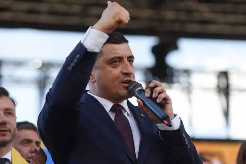 Bărbat în costum vorbește la microfon, ridicând pumnul